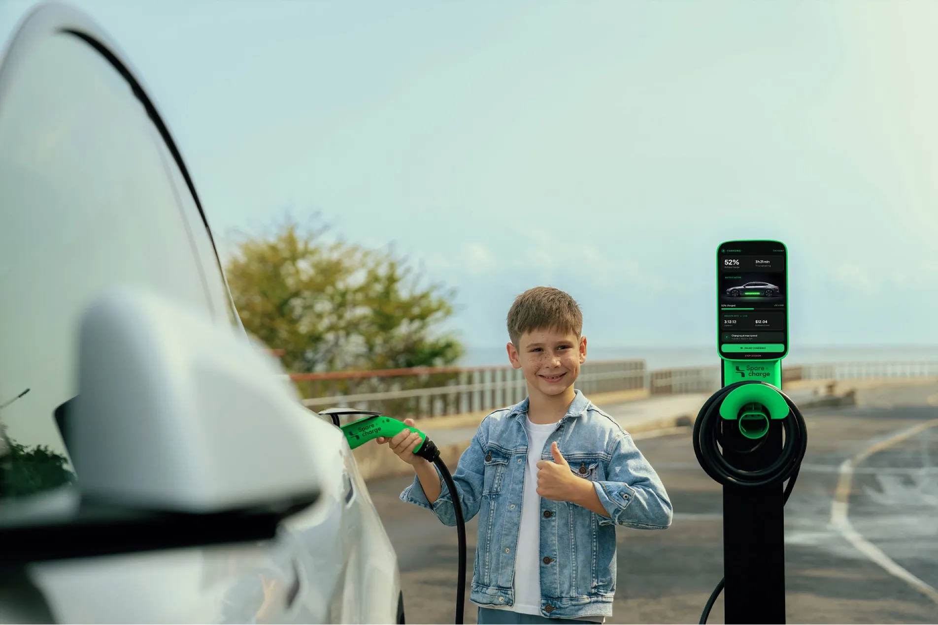 Boy waving next to a SpareCharge charger by the sea