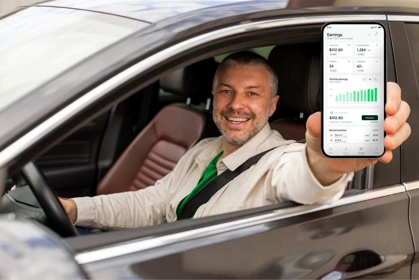 Smiling driver holding up the SpareCharge app in his car