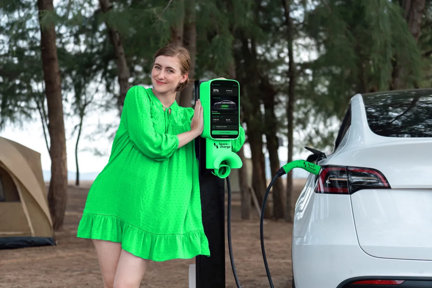 Woman in a green dress at a SpareCharge charger near a forest
