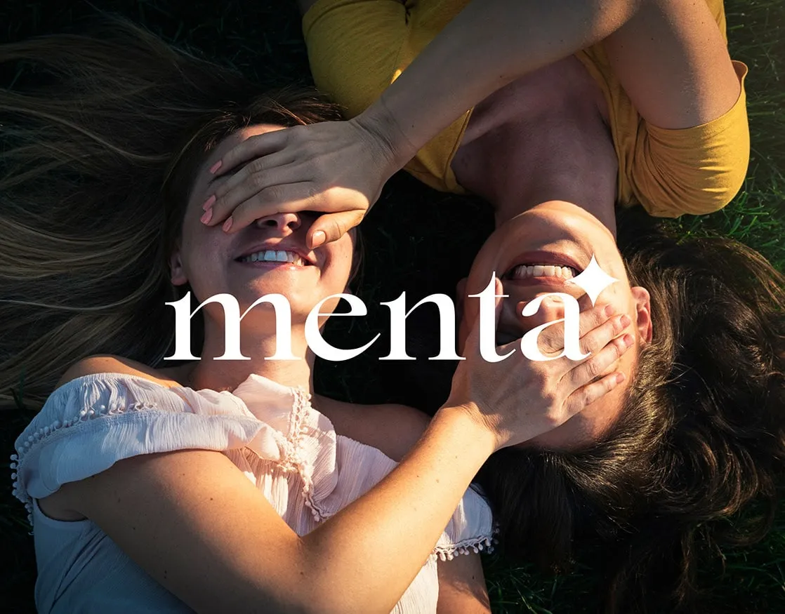 Menta wordmark over two smiling women lying on the grass