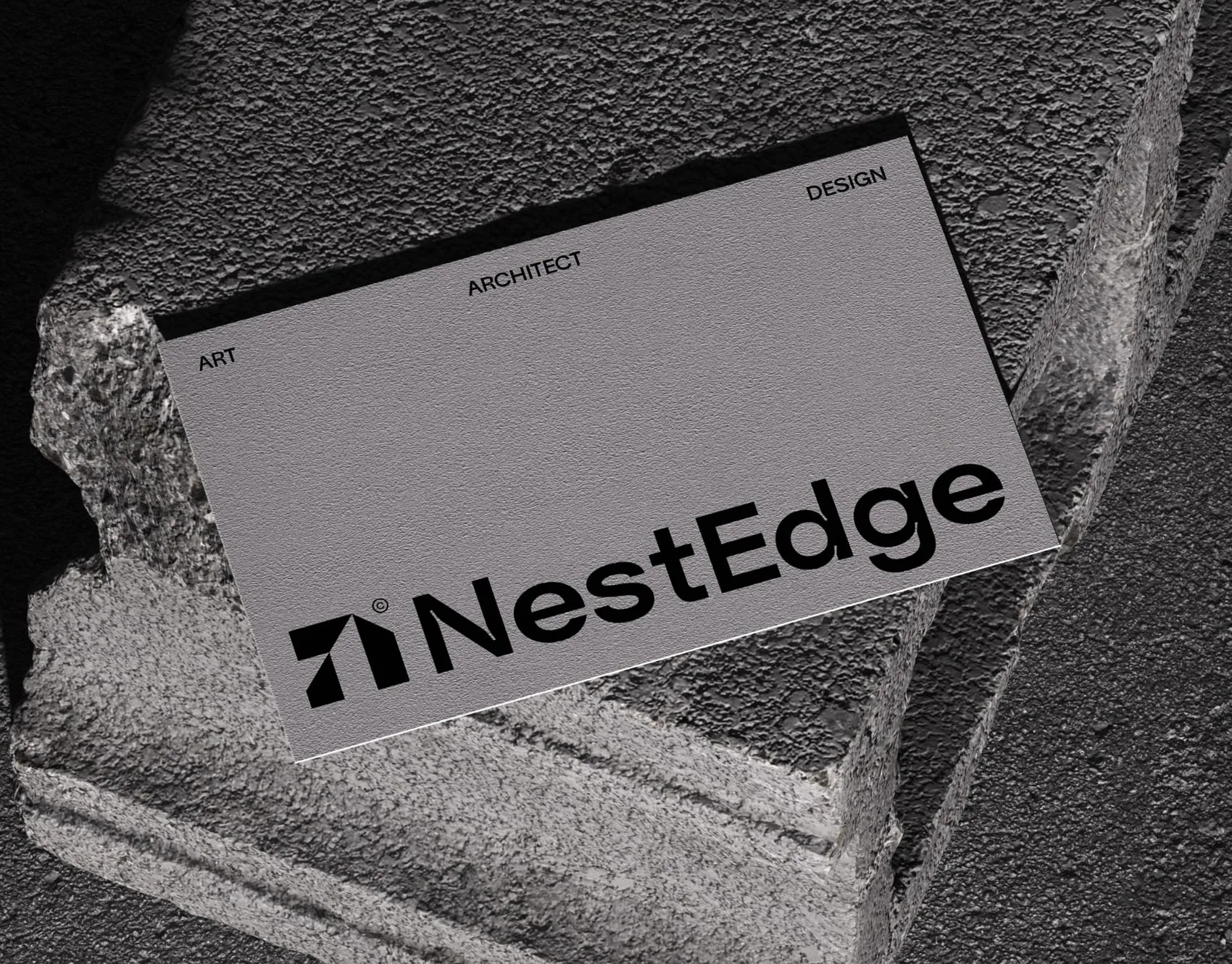 Grey business card for the architecture studio NextEdge on rough concrete