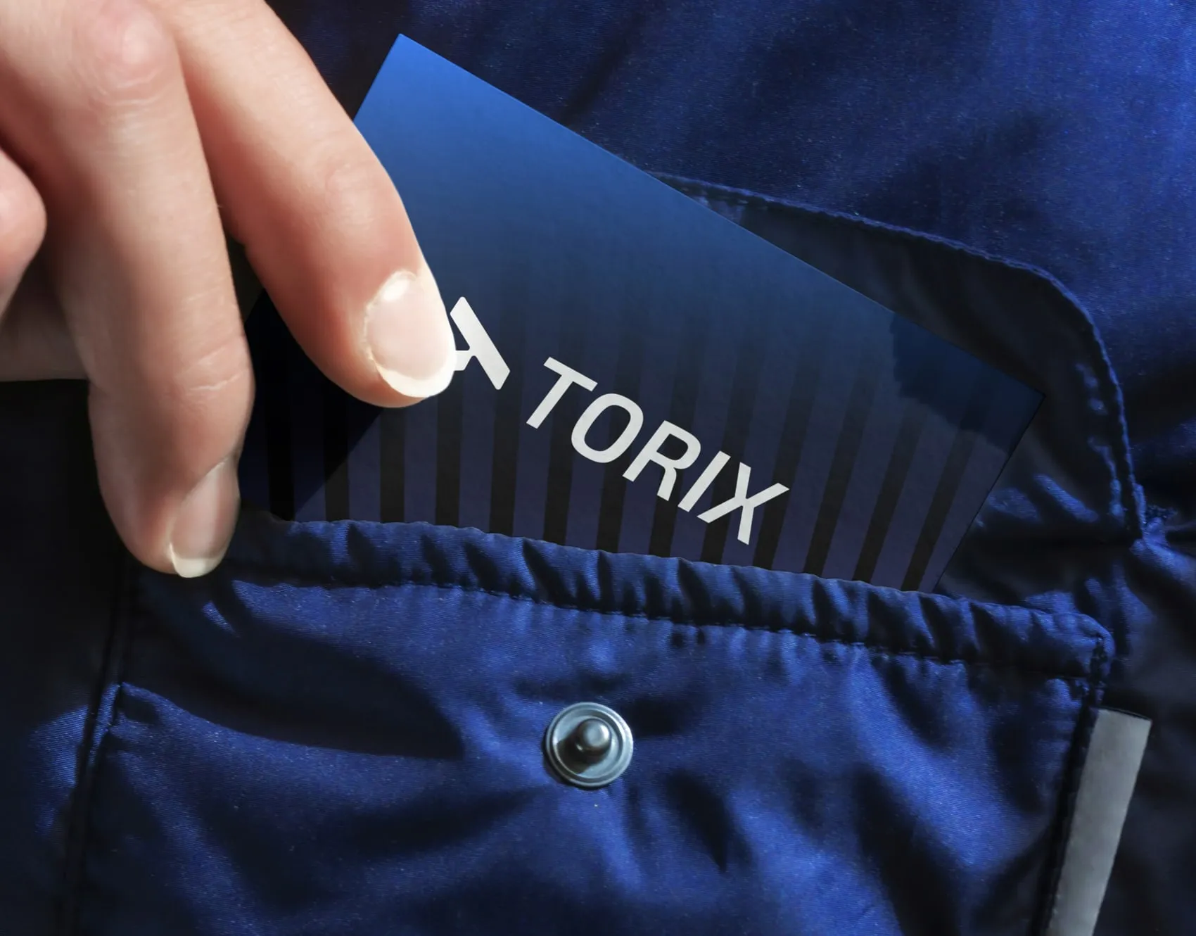 Hand holding a blue TORIX card at the pocket of a navy jacket