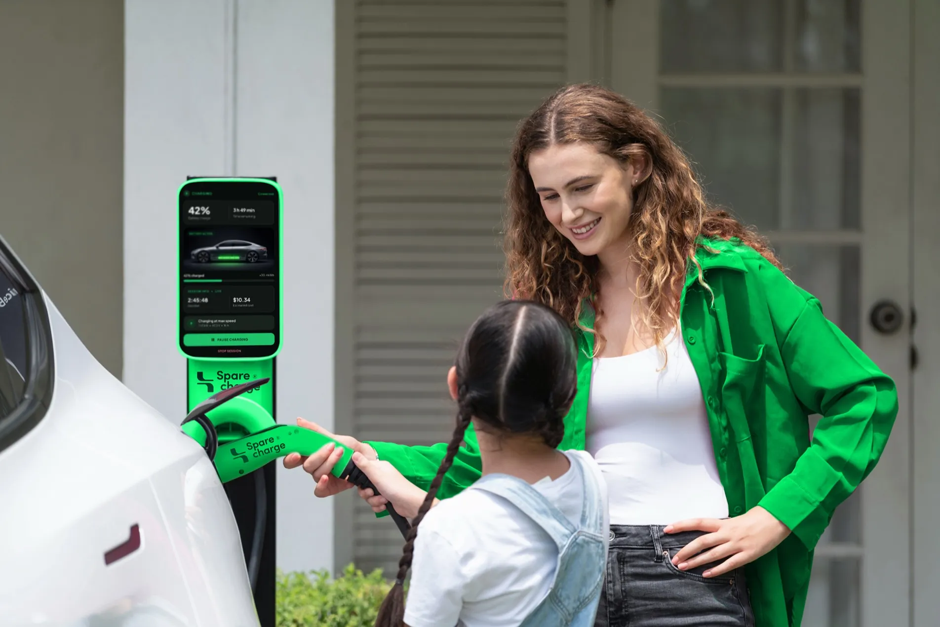 Mother and daughter at a SpareCharge charger in front of their home