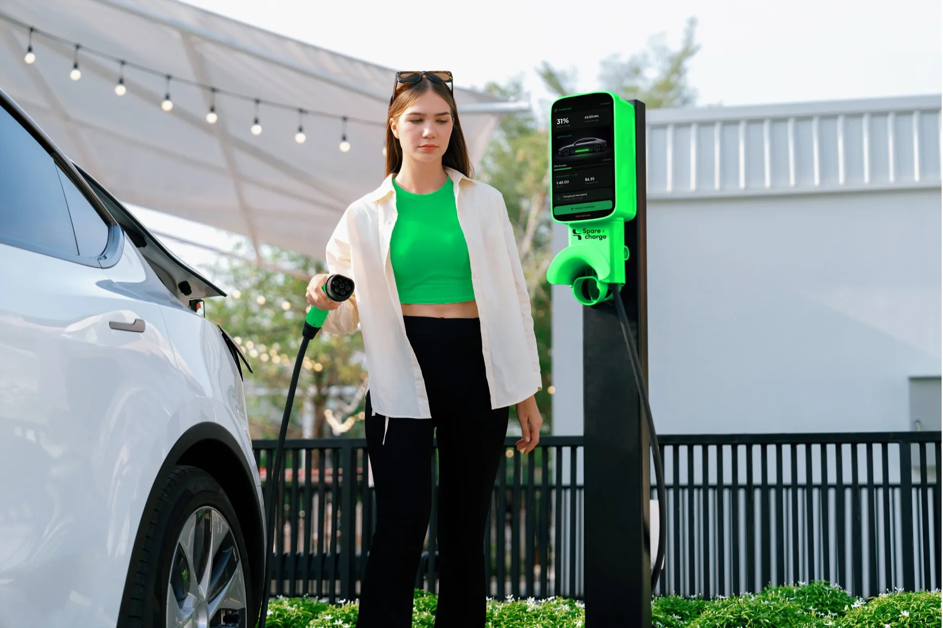 Woman beside her electric car and a SpareCharge charger outside a house