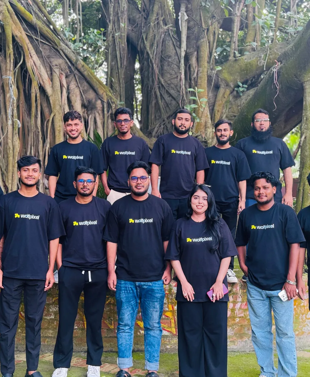 The Wolfpixel team in matching black T-shirts under large banyan trees