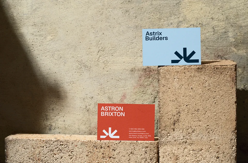 Blue and orange Astrix Builders business cards resting on concrete blocks