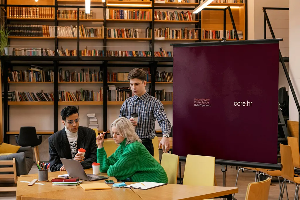 Team working in a library next to a core.hr roll-up banner