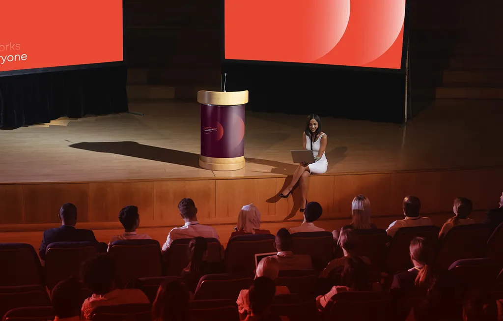 Speaker on a stage in front of a core.hr screen and audience