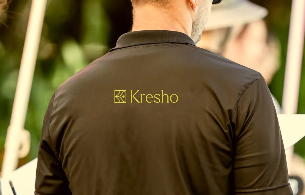 Back of a farmer’s dark polo shirt with the Kresho logo