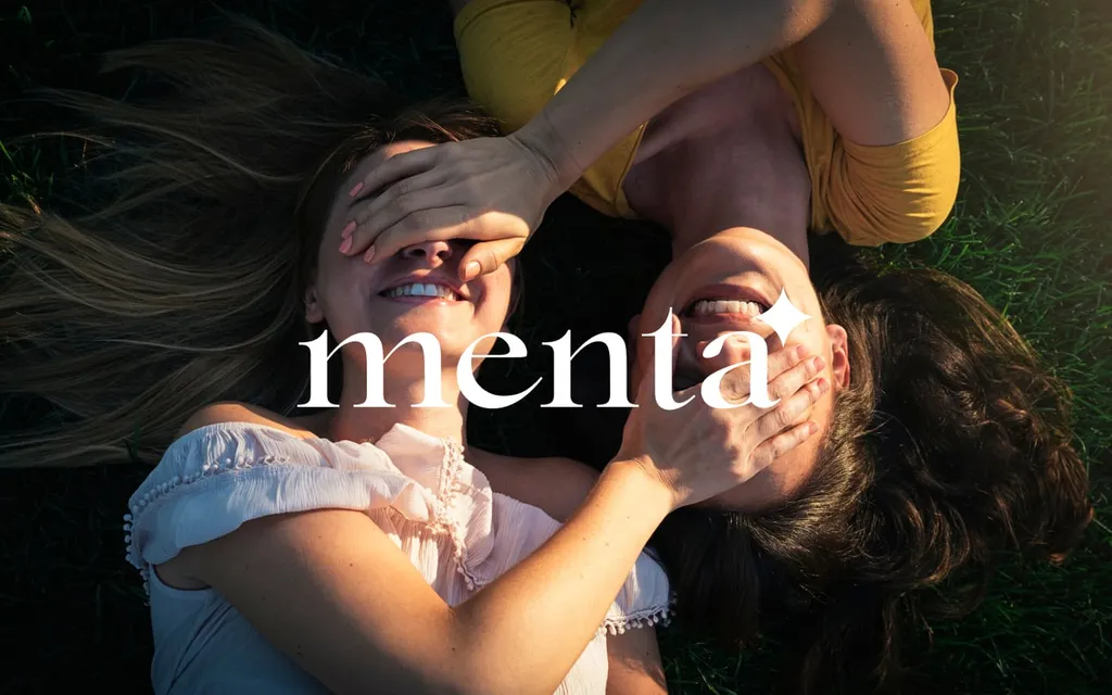 Menta wordmark over two smiling women lying on the grass
