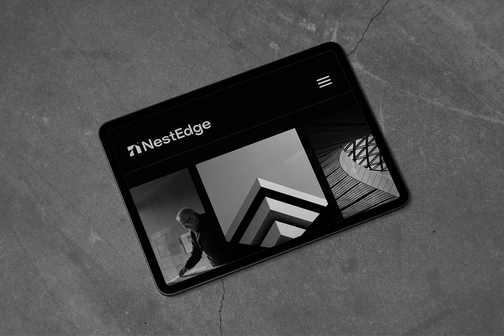 NestEdge website on a tablet lying on cracked concrete, with the logo above three architecture photos