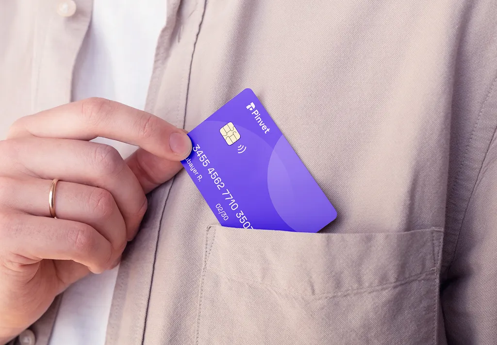 Hand sliding a purple Pinvet card into the chest pocket of a beige shirt
