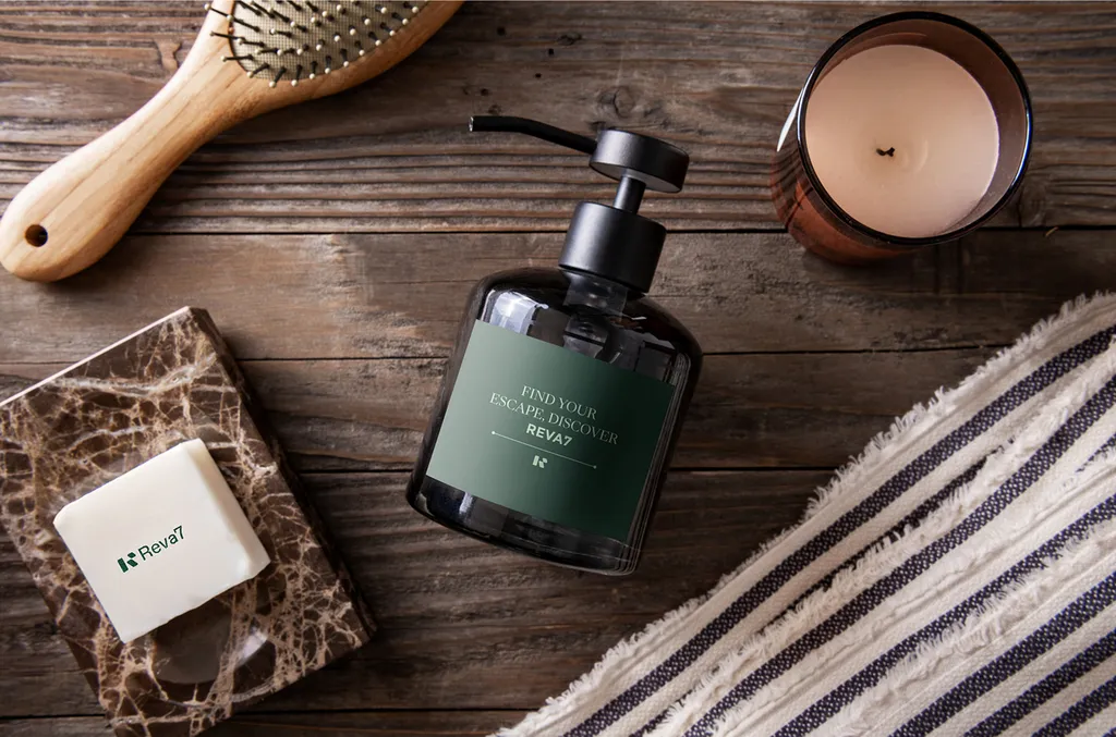 Reva7 amenities on a wooden table: soap dispenser, soap bar, brush and candle