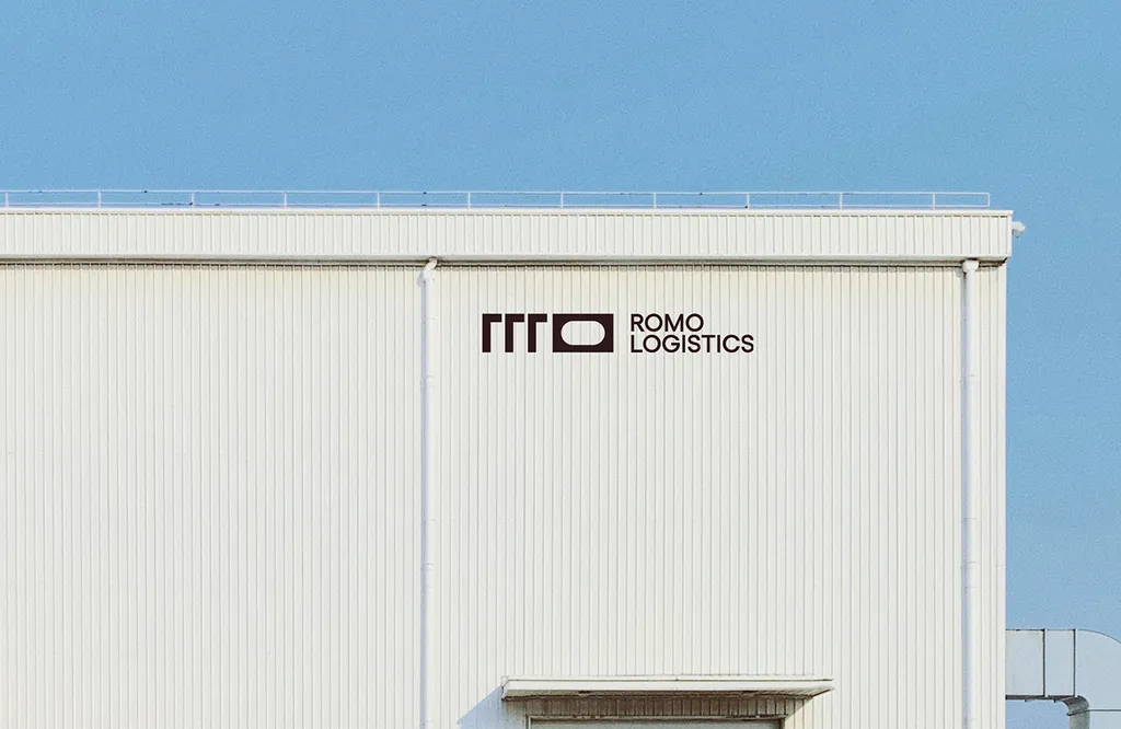 ROMO Logistics logo on a white warehouse against a blue sky