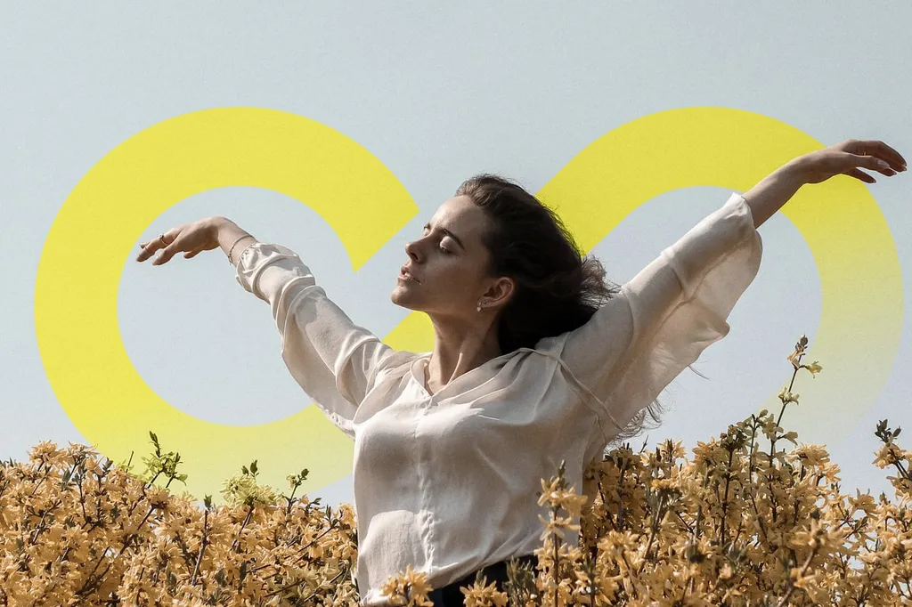 Woman with open arms in a flower field in front of a large yellow infinity shape