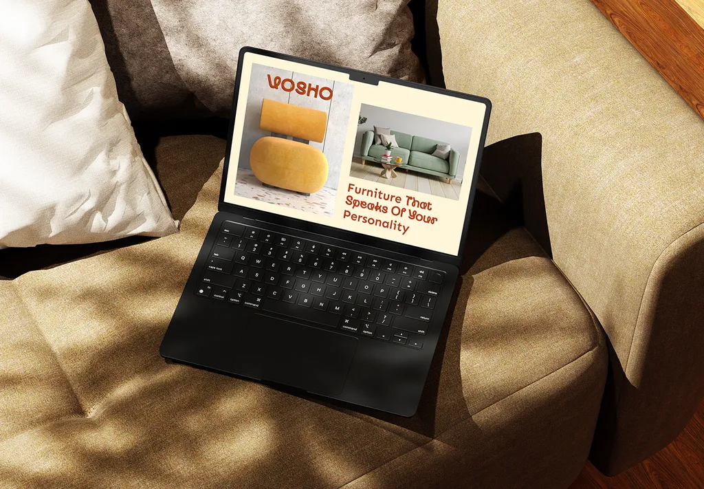 Laptop on a beige sofa showing the Vosho site: a yellow chair, a green sofa and “Furniture That Speaks Of Your Personality”