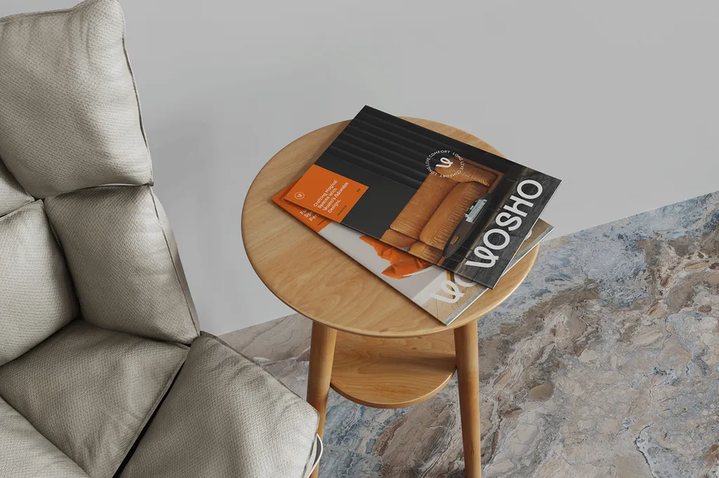 Vosho magazines on a round wooden side table next to a gray armchair, with the “Long Live Comfort” badge