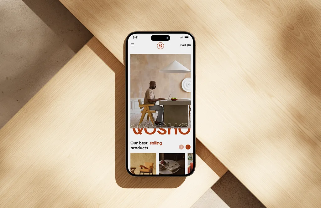 Phone on light wood showing the Vosho mobile store: a man working at a laptop at a table, above a product carousel