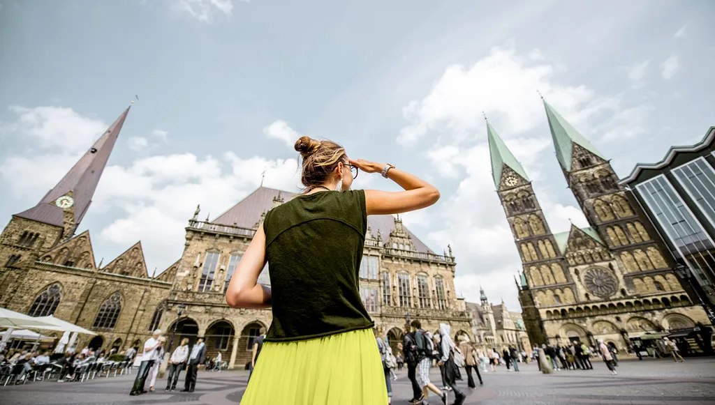 Woman in a lime skirt raising her arms in front of a gothic cathedral