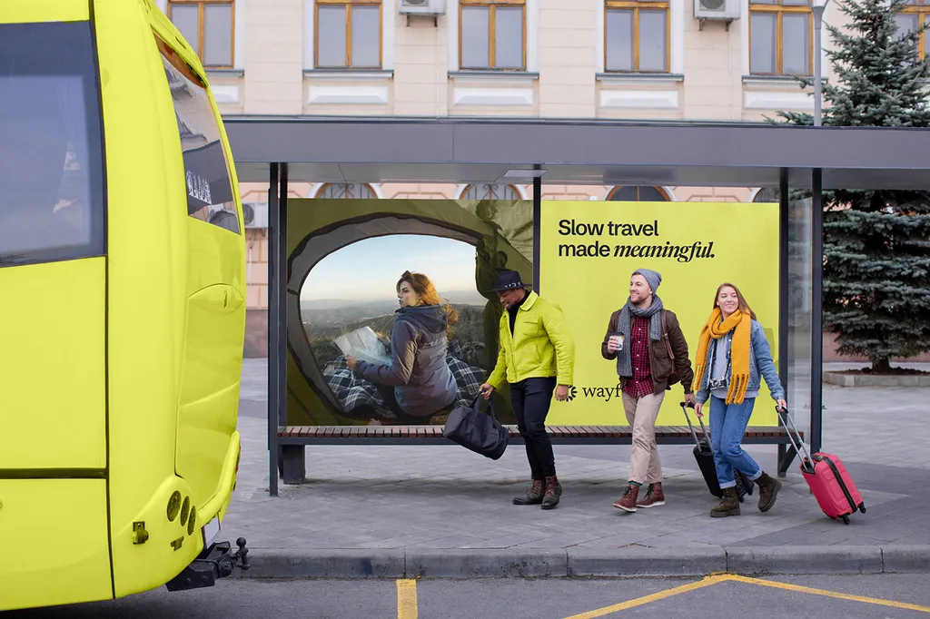 Wayfare bus shelter ad, “Slow travel made meaningful”, with travellers walking past