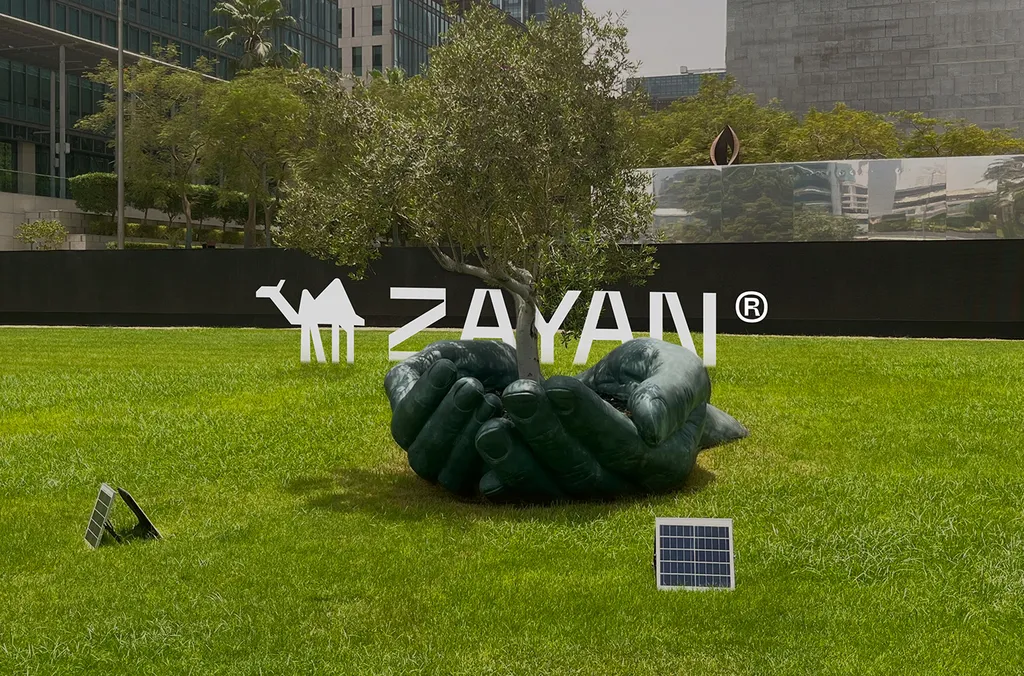 ZAYAN logo on a billboard above a park with a sculpture and a solar panel
